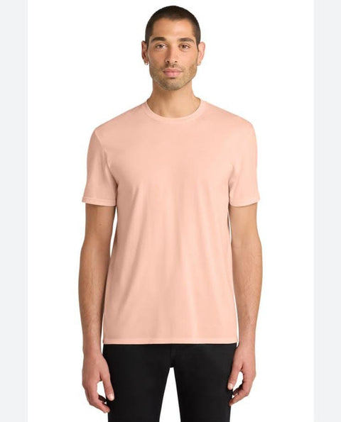 Man wearing a light pink t-shirt and black pants on a white background