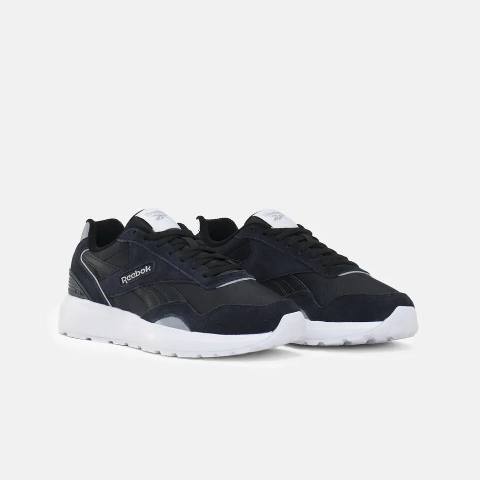 A pair of Reebok sneakers in navy blue suede and mesh with white midsoles, shown from a three-quarters angle on a light gray background.