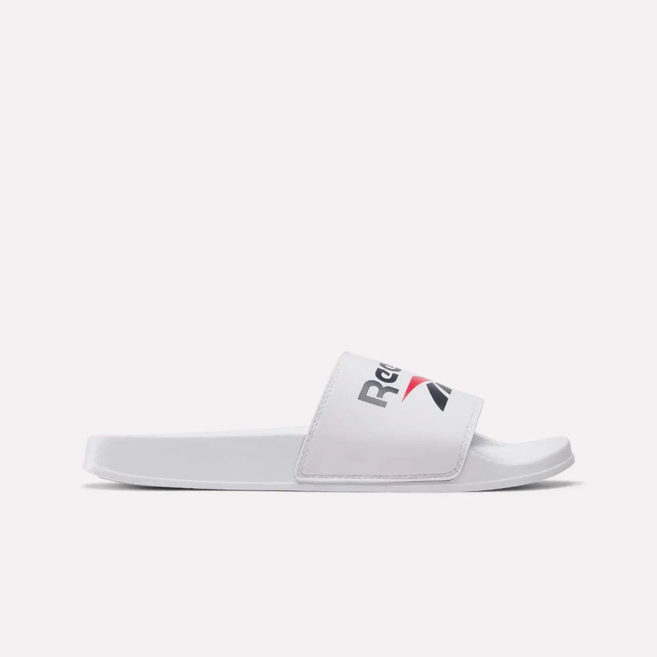 A single Reebok slide sandal in white, featuring a white strap with the Reebok logo in black and red, set against a light gray background.