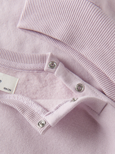 Close-up of a pink garment with buttons and a label.