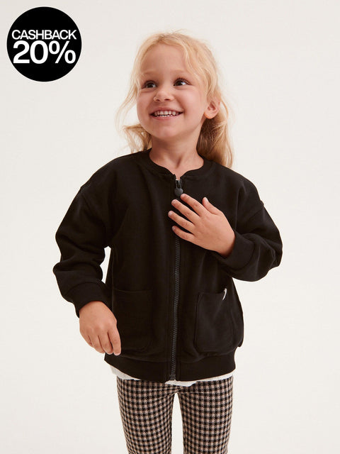 Child wearing a black jacket on a plain background