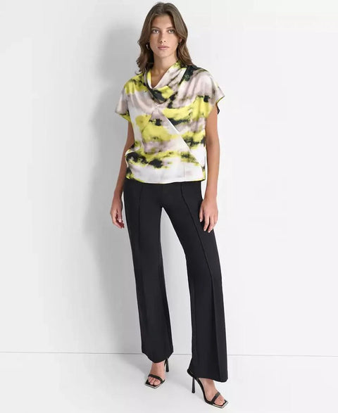 Woman wearing a colorful top and black pants on a white background