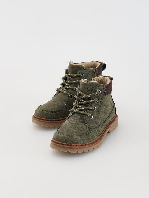 Pair of green suede boots with brown soles on a white background
