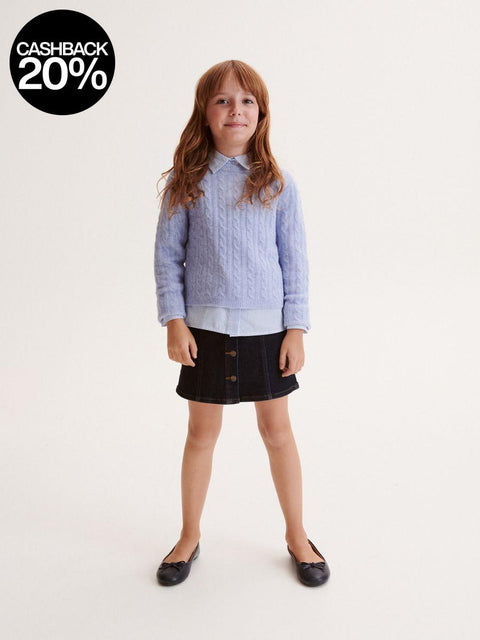 Young girl wearing a light blue sweater and black skirt on a white background