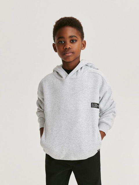 Child wearing a gray hoodie with a brand logo on a white background