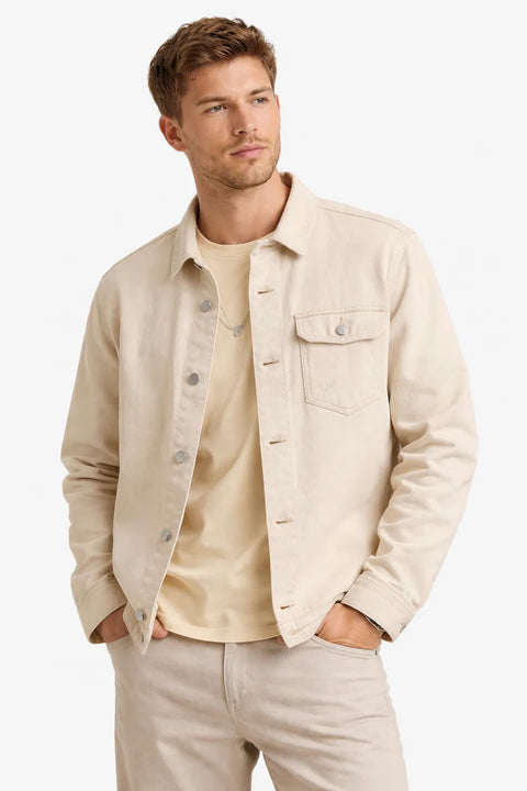 Man wearing a beige jacket over a light shirt with a plain background