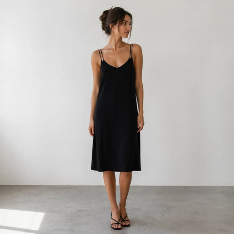 Woman wearing a black slip dress against a plain background