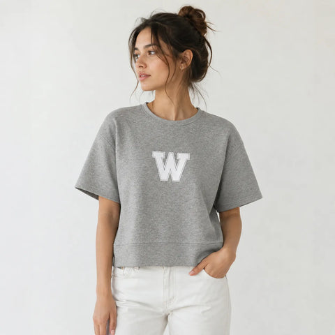 Woman wearing a gray sweatshirt with a white 'W' logo on a plain background