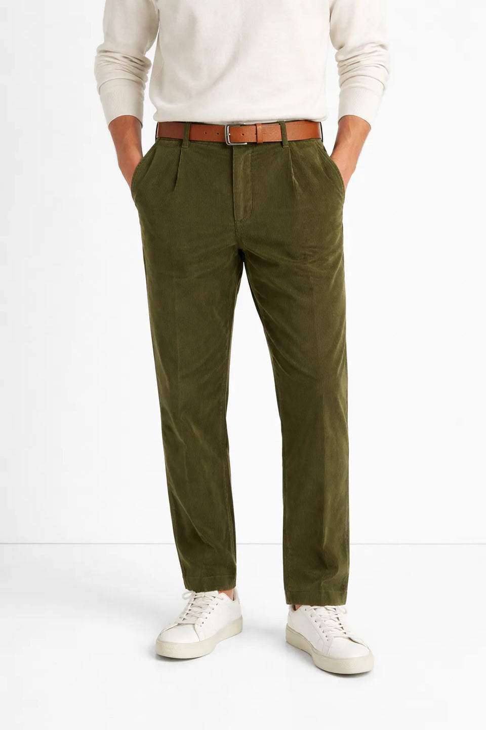 Person wearing olive green pants with a white shirt and white sneakers on a white background