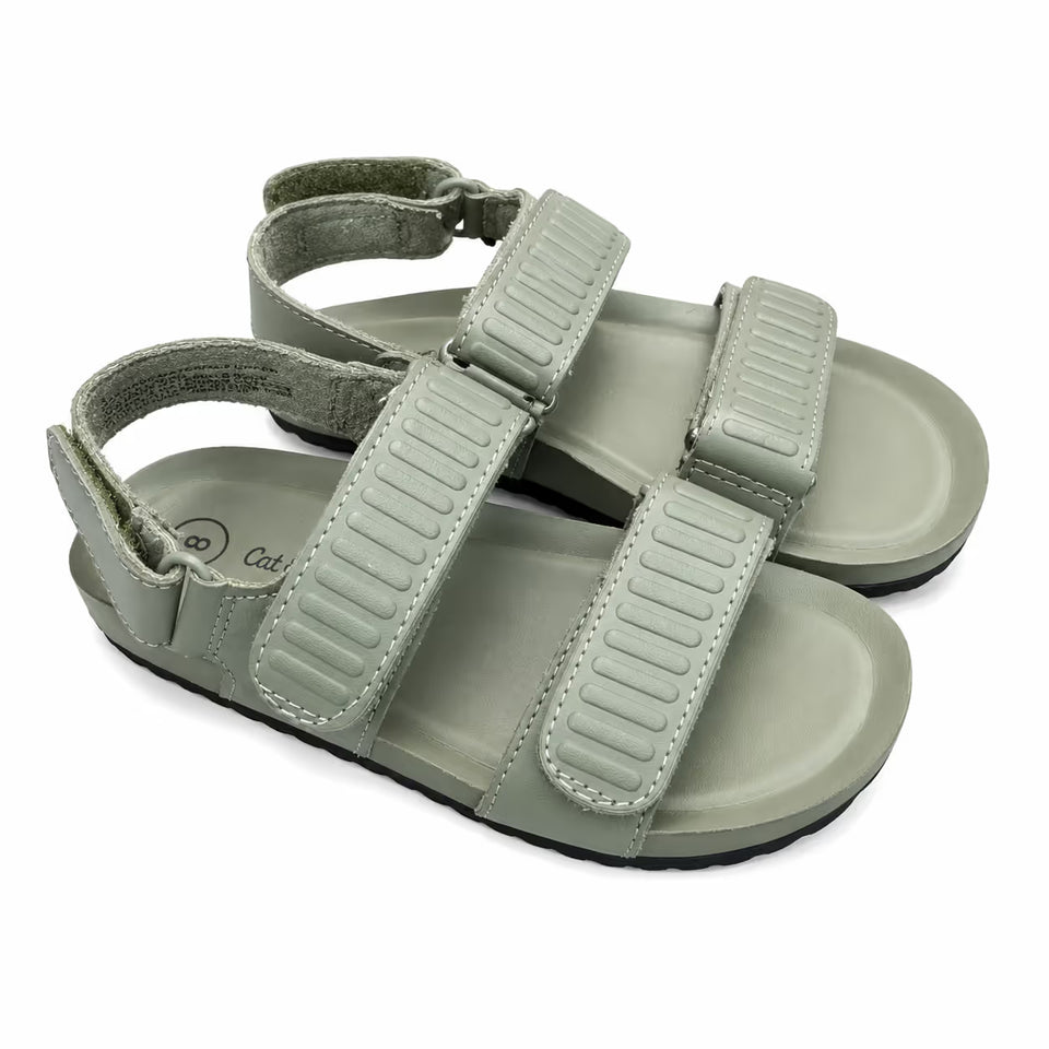 A pair of children's double-strap sandals in a muted sage green color, featuring textured straps and a contoured footbed, shown on a plain white background.