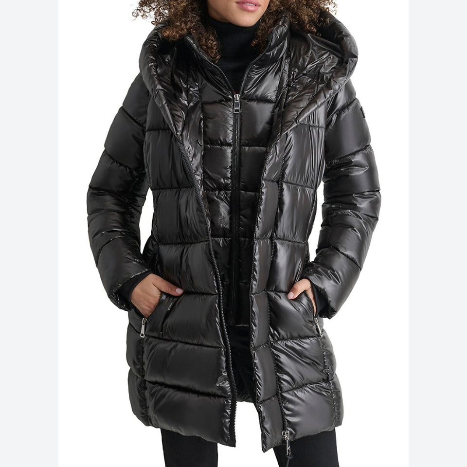 A woman wearing a shiny black hooded puffer jacket with horizontal quilting, shown from the shoulders down against a plain white background.