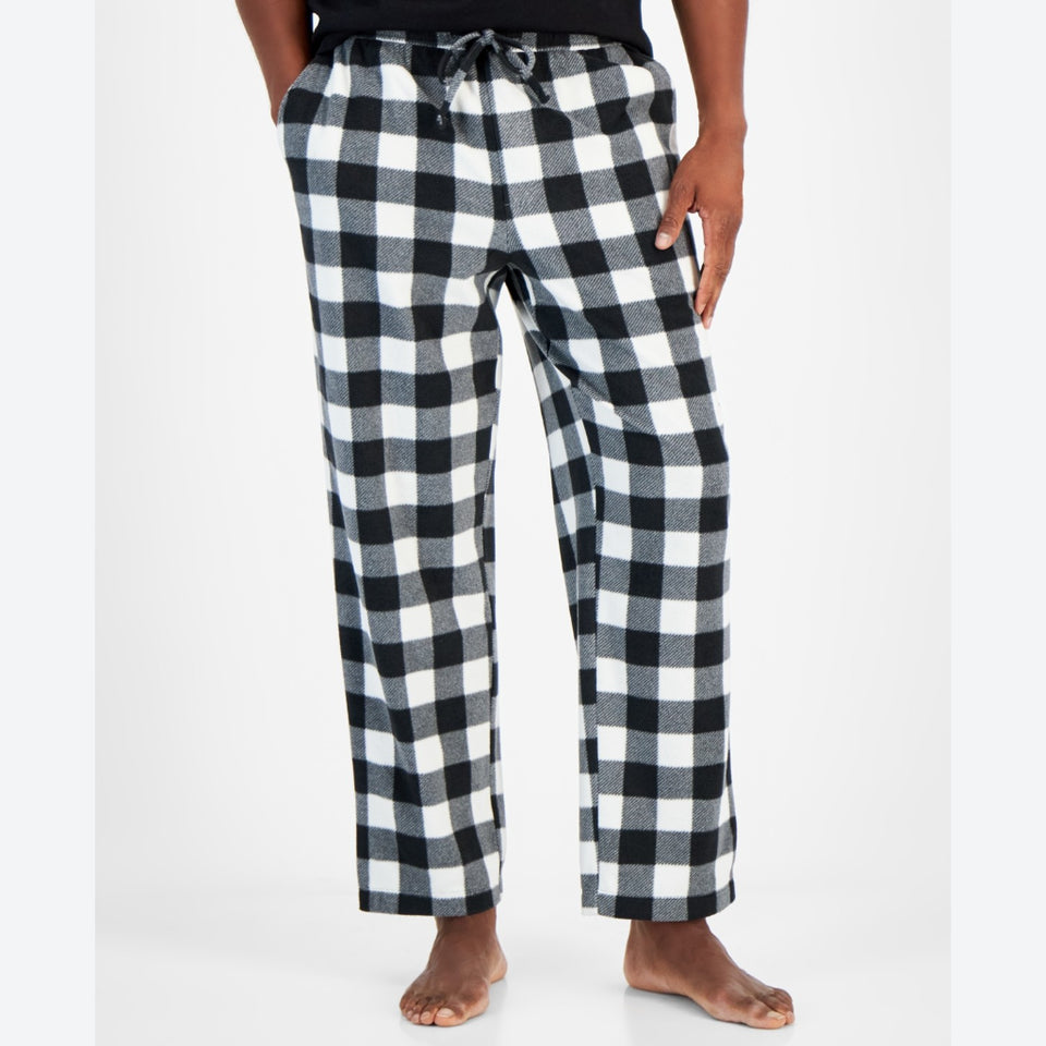 A person wearing black and white buffalo plaid lounge pants with a drawstring waist, shown from the waist down against a light gray studio background.