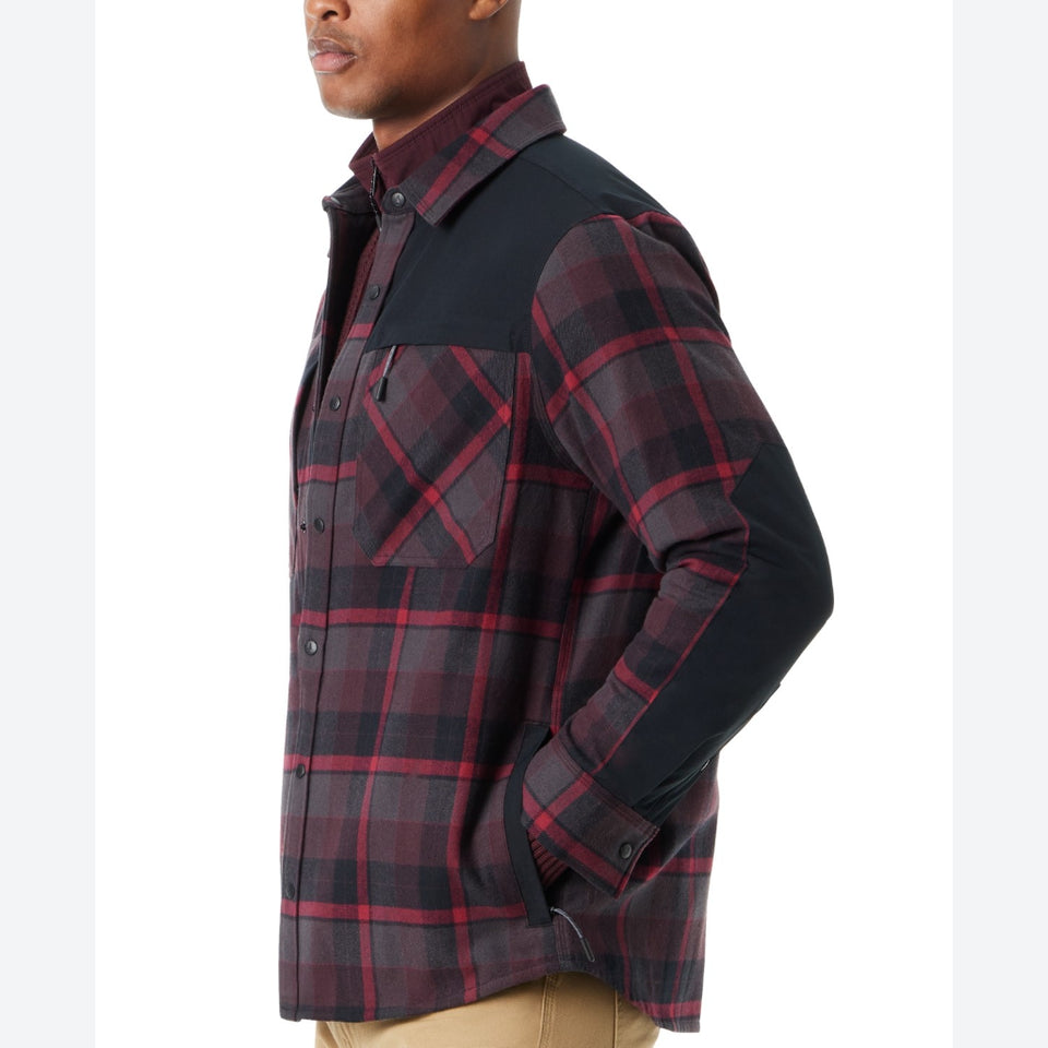 A man wearing a long-sleeve button-up shirt with a dark red and black plaid body and solid black sleeves, shown in a side profile against a white background.
