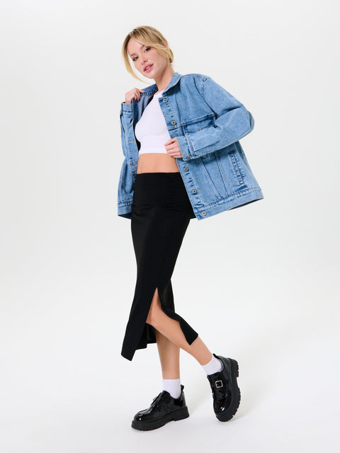 Woman wearing a denim jacket, white top, black skirt, and black shoes on a white background