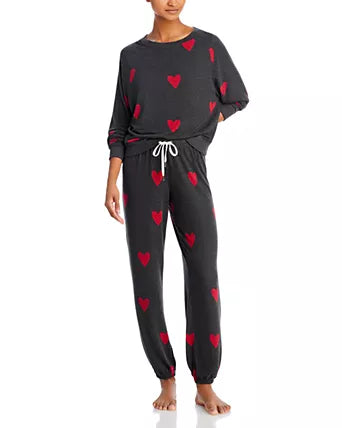 Woman wearing a dark gray pajama set with red heart patterns on a white background