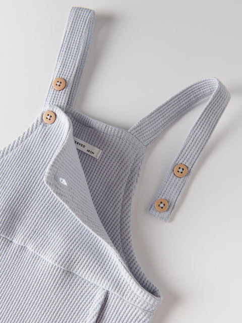 Gray knitted baby romper with wooden buttons on a light gray background