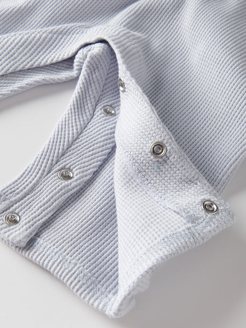 Close-up of a textured gray cardigan with button details on a light background