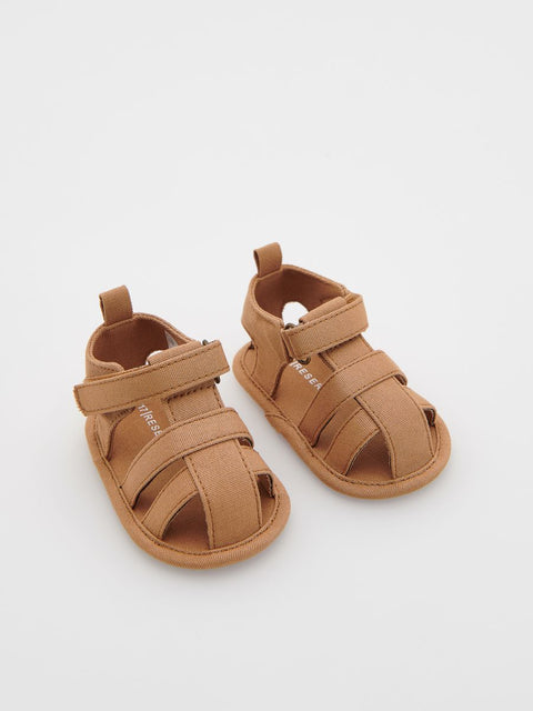 Pair of brown baby sandals on a light gray background
