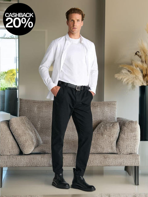 Man in a white shirt and black pants standing in a modern living room.