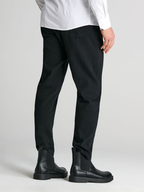Person wearing black pants and black boots on a light gray background