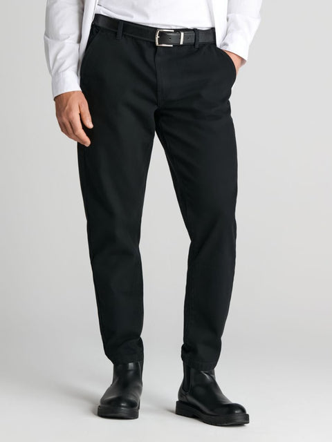 Person wearing black dress pants with a white shirt on a light gray background