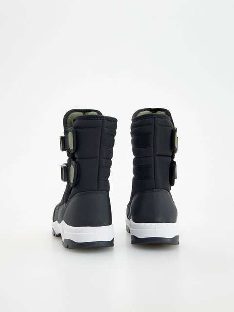Black winter boots with white soles on a light gray background
