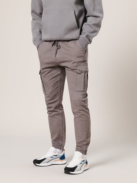 Person wearing a gray hoodie and pants with white sneakers on a light background