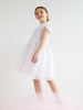 Young girl wearing a white dress with lace details on a light background