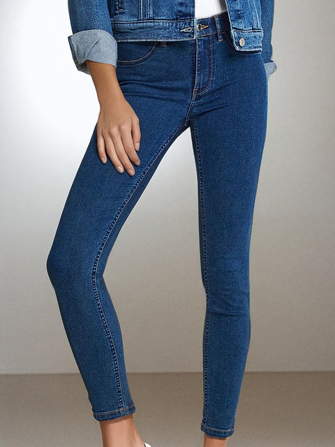 Blue jeans worn by a person on a plain background