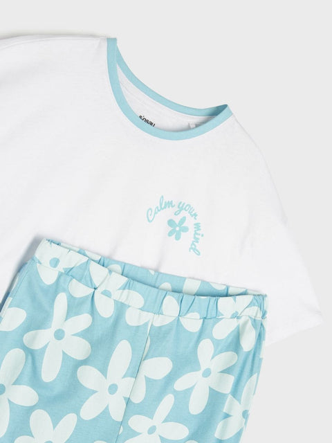White t-shirt with blue trim and floral shorts on a white background