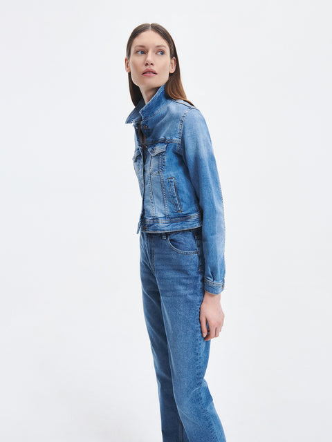 Woman wearing a blue denim jacket and jeans on a white background