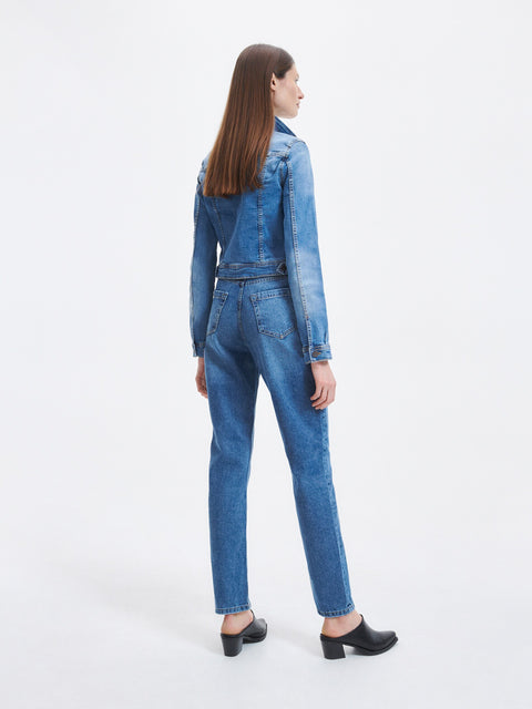 Woman wearing a blue denim jumpsuit on a white background