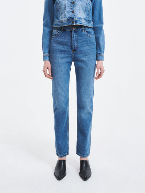 Person wearing blue jeans and a denim jacket on a white background