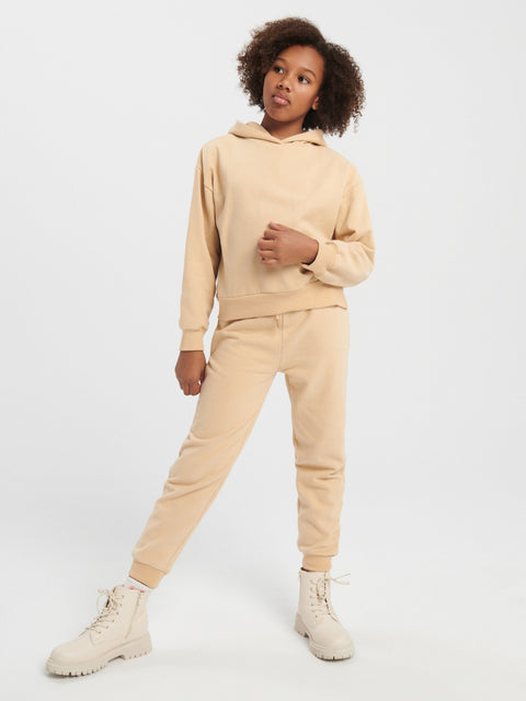 Person wearing a beige tracksuit on a white background