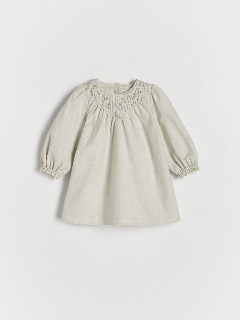 Beige dress with smocked bodice on a light gray background