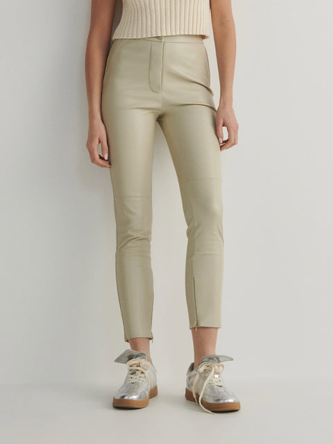 Person wearing beige pants and silver shoes on a light gray background