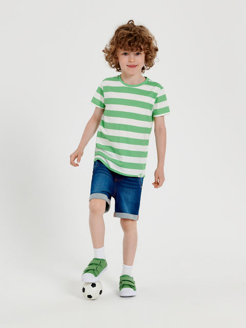 Child wearing a green and white striped shirt with blue shorts on a white background