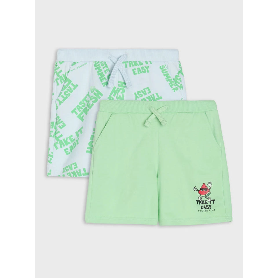 Two pairs of kids' shorts displayed together on a light gray background. The front pair is mint green with a drawstring waist and a small watermelon graphic with 'TAKE IT EASY' text.
