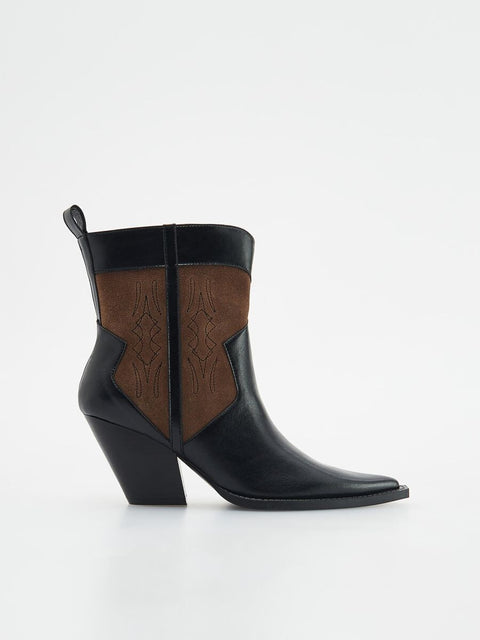 Black ankle boot with brown leather patch on a white background