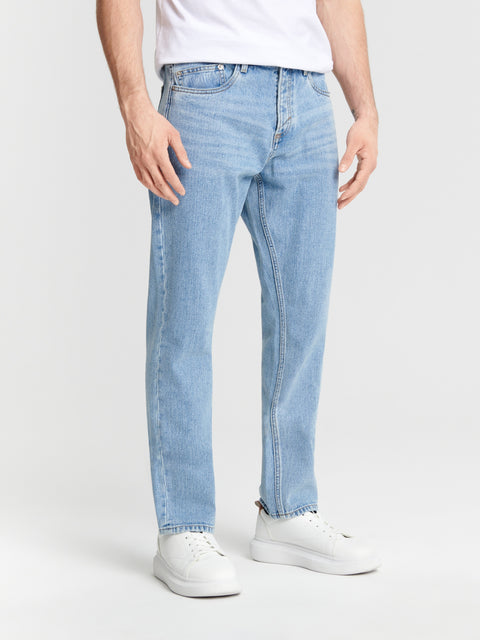 Person wearing light blue jeans and white sneakers on a white background