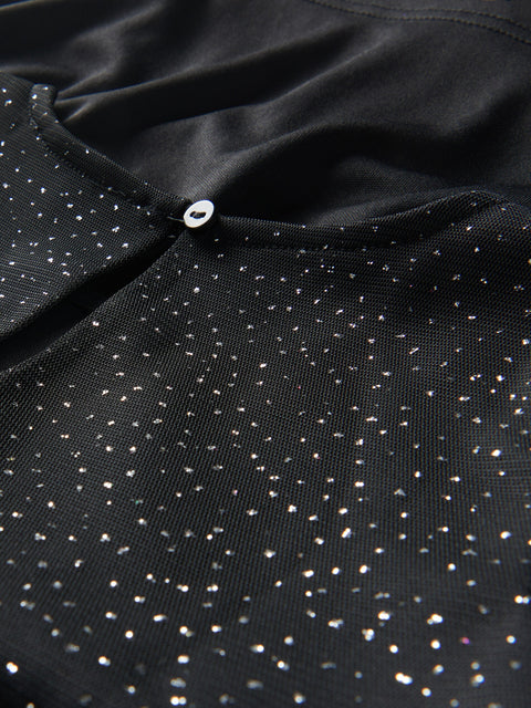 Close-up of a black fabric with small white dots and a button detail.