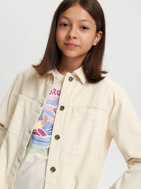 Young girl wearing a beige jacket over a colorful shirt on a white background