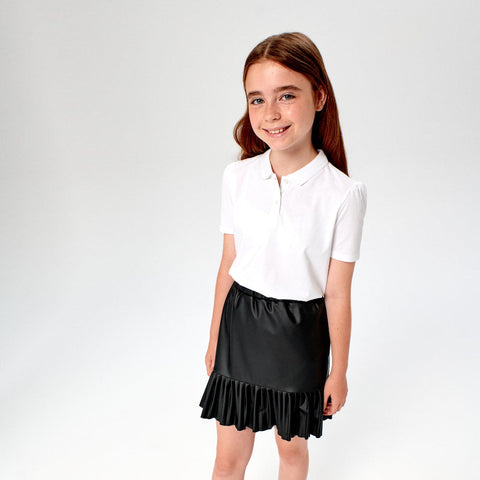 Young girl wearing a white polo shirt and black ruffled skirt on a white background