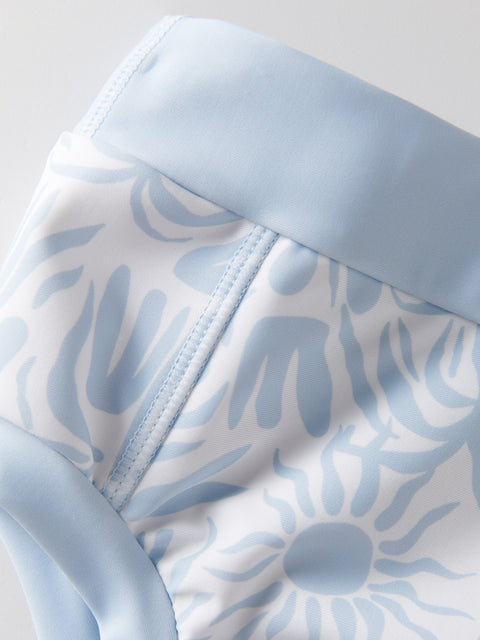 Close-up of a baby outfit with blue floral pattern and light blue trim on a white background