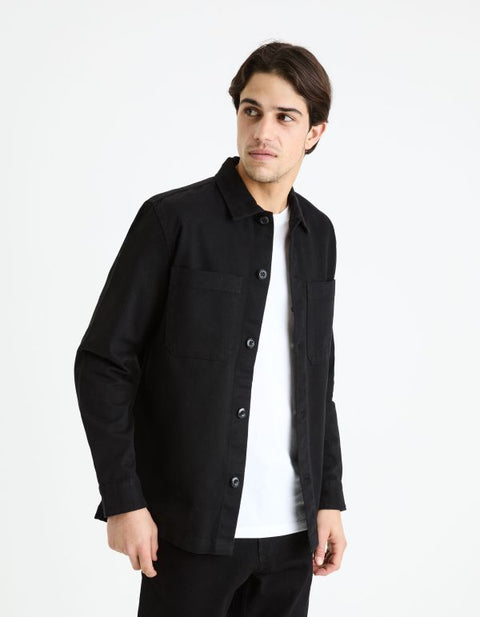 Man wearing a black jacket over a white shirt on a white background