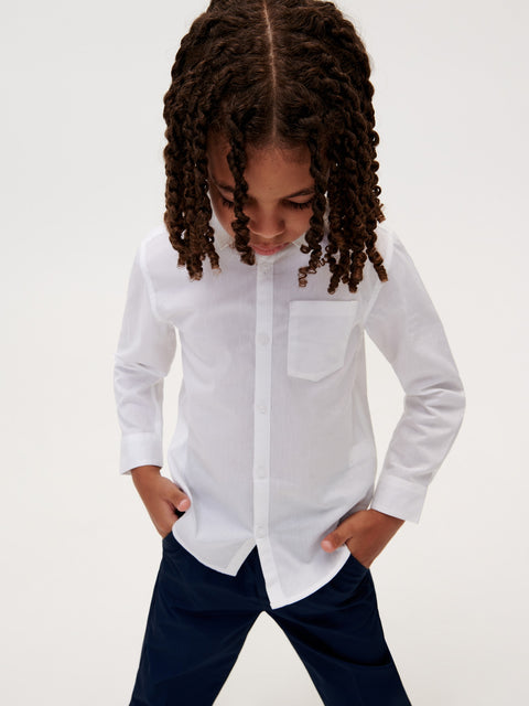Child wearing a white button-up shirt with a plain background