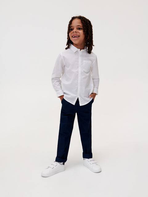 Child wearing a white shirt and navy pants on a white background