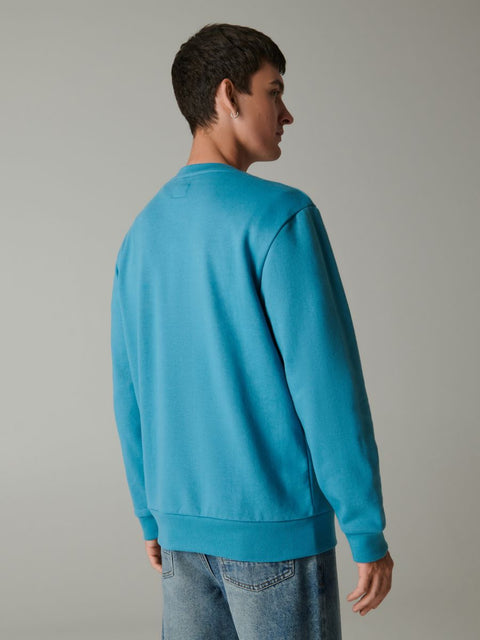 Person wearing a blue sweatshirt against a plain background