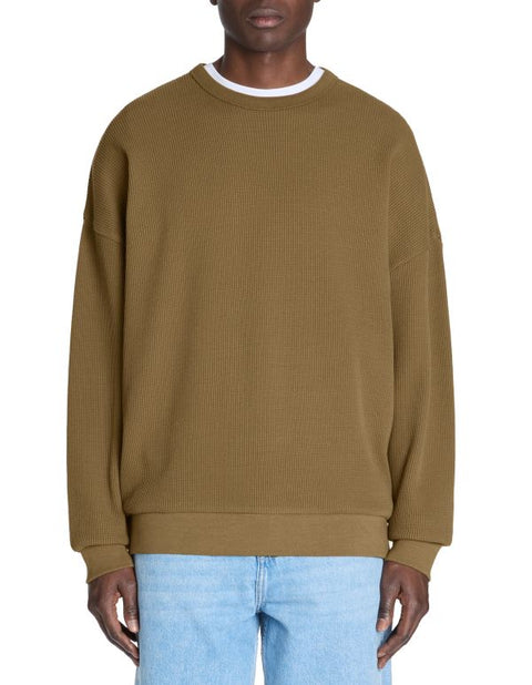 Person wearing a brown ribbed sweater and light blue jeans on a white background