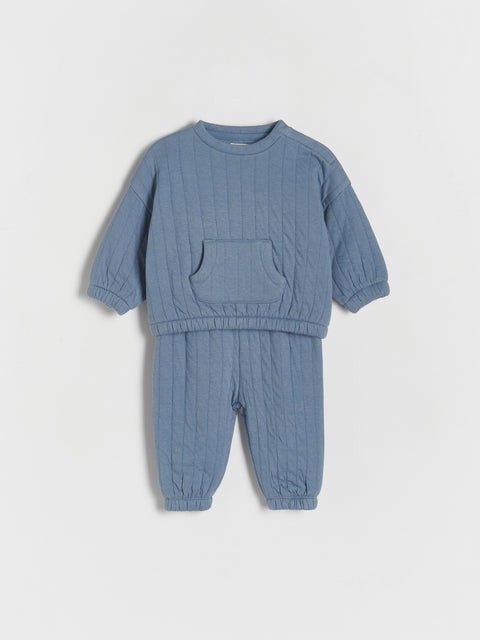 Blue baby outfit with sweater and pants on a light gray background